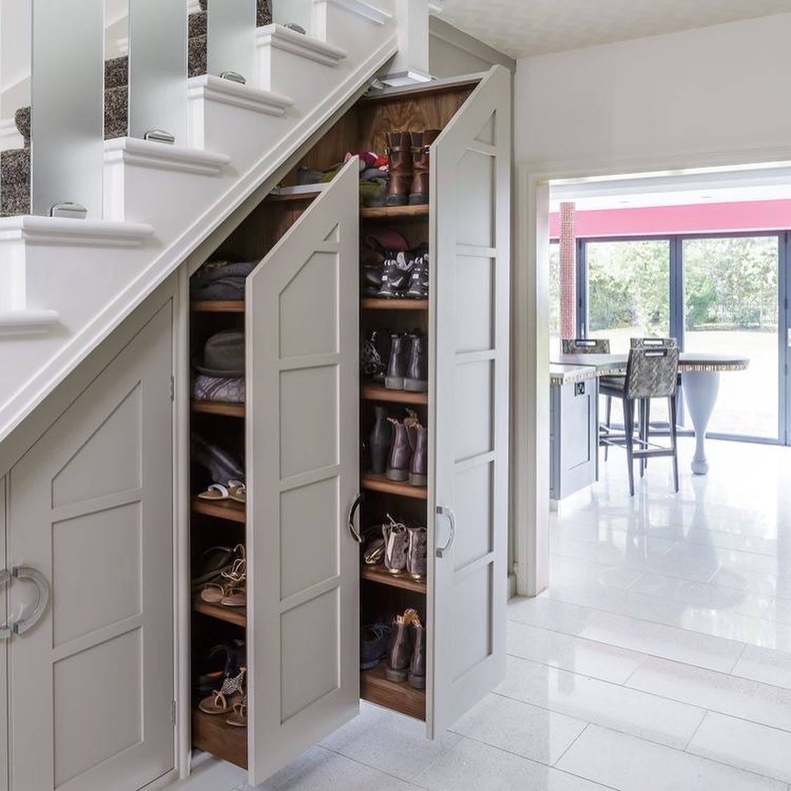 Custom-built under-stairs cabinet with multiple shelves designed for shoe storage.