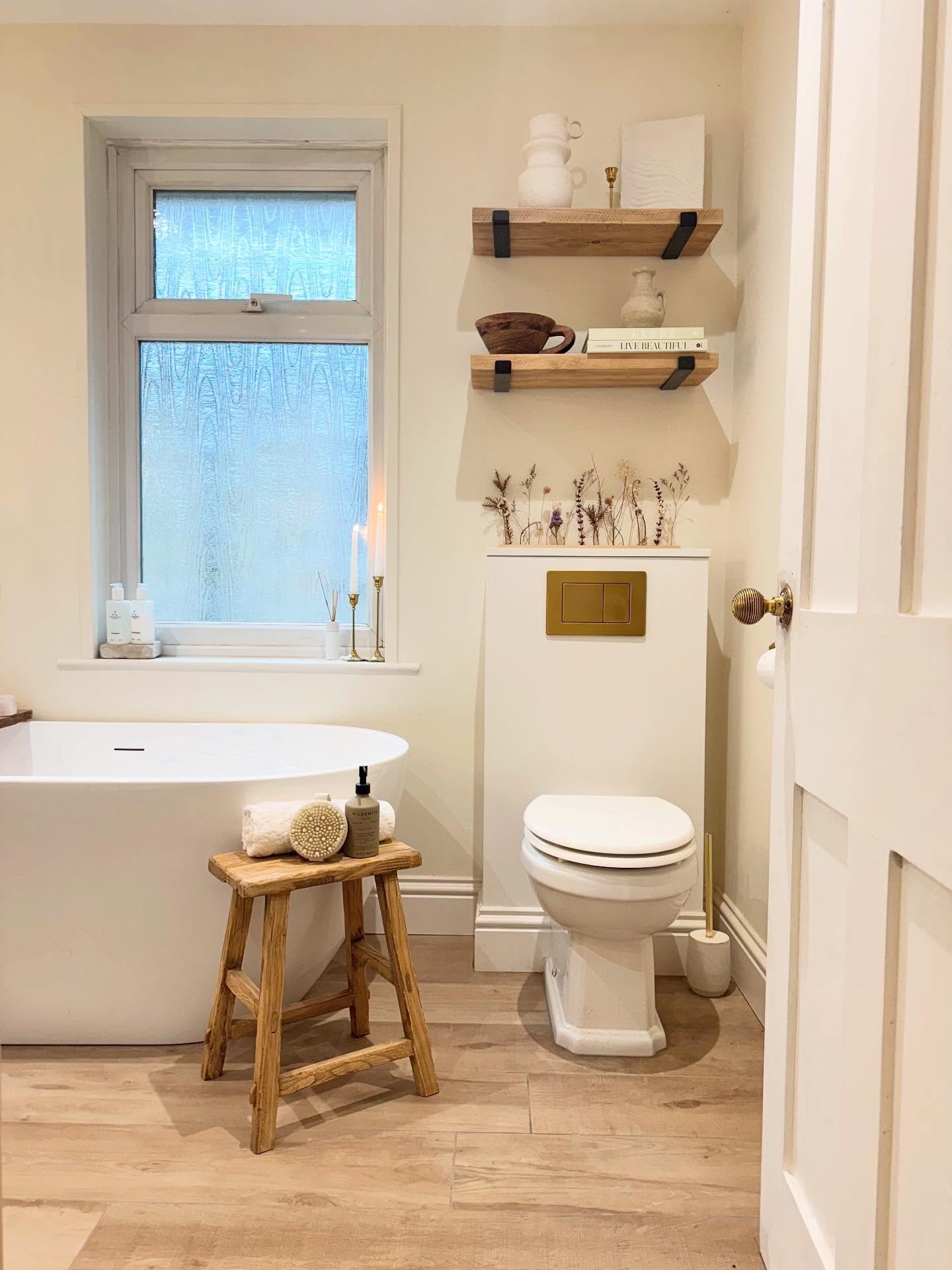 Two thick wood shelves held up by dark metal brackets above a white bathroom fixture, styled with books and decor.