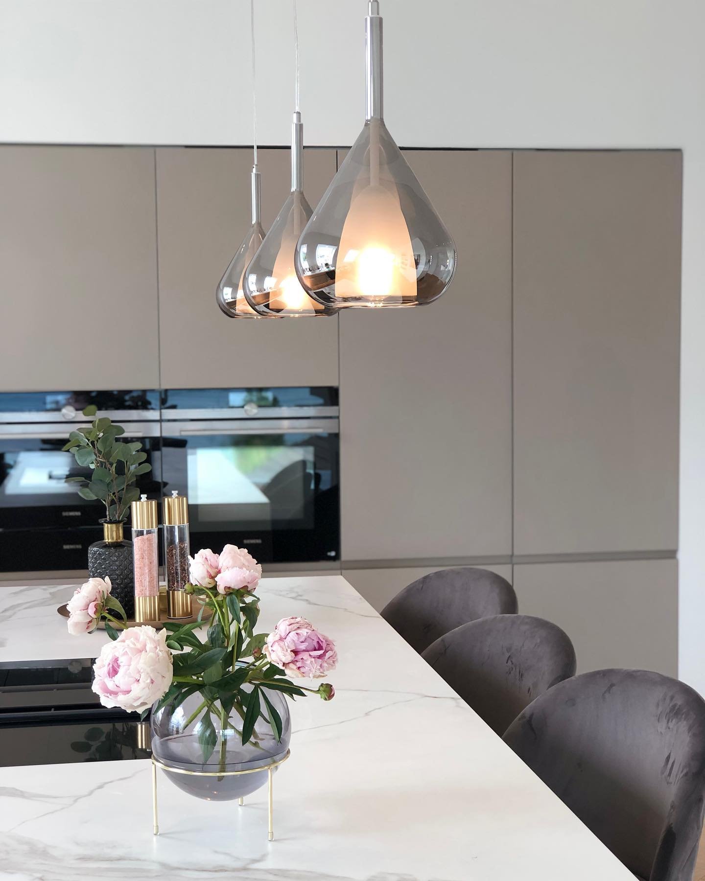 Trio of black metal wire cage pendants suspended above a large white farmhouse kitchen island.