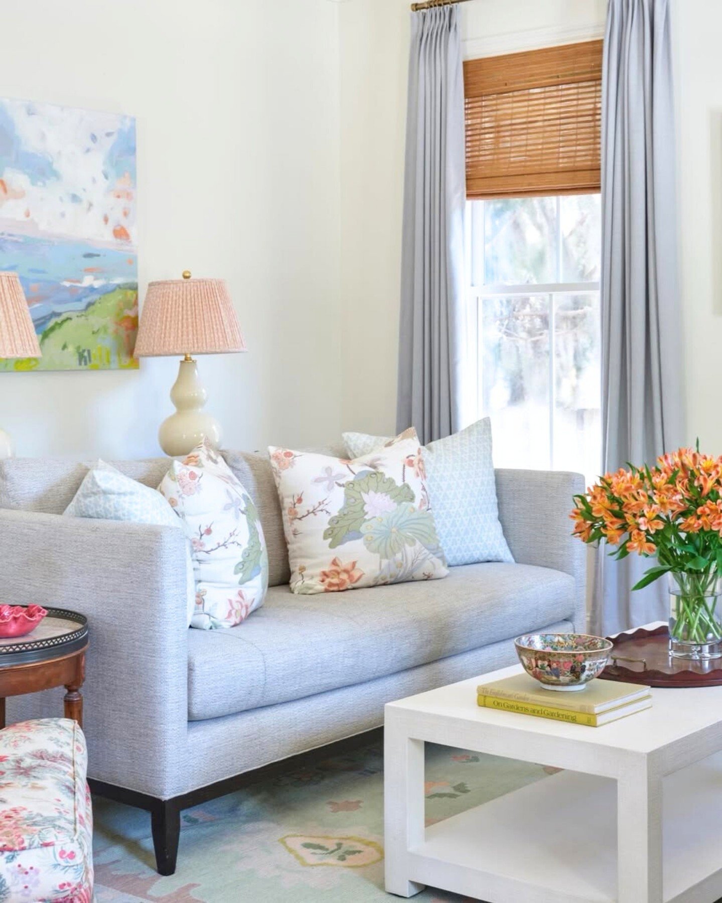 Soft blue-gray pleated curtains layered over a natural woven bamboo shade in a light and airy living room.