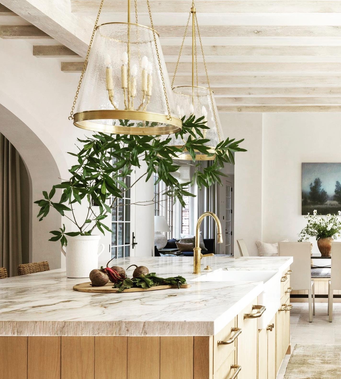 Sophisticated bronze and clear glass lantern pendant light illuminating a marble-top island.