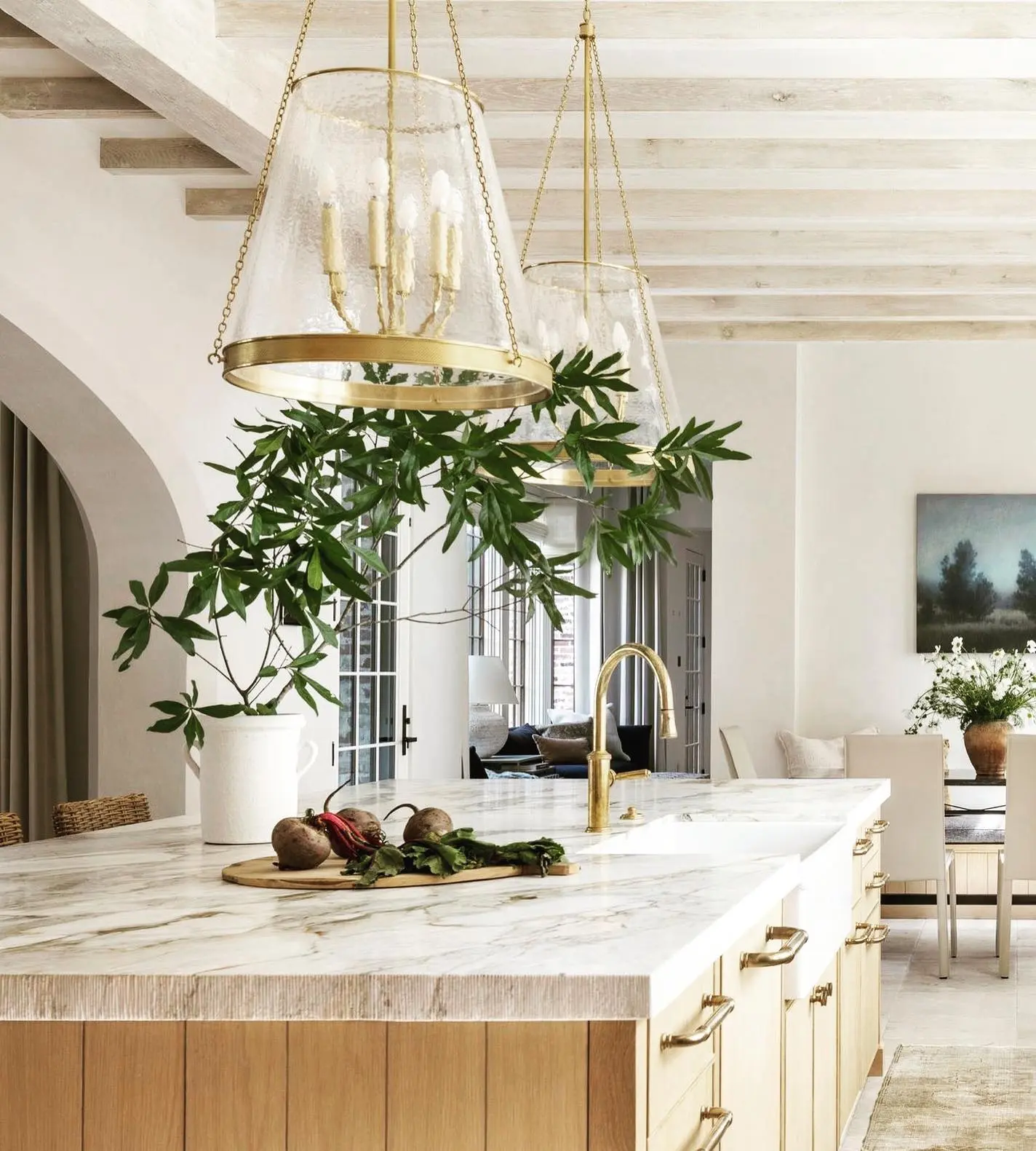 Sophisticated bronze and clear glass lantern pendant light illuminating a marble-top island.