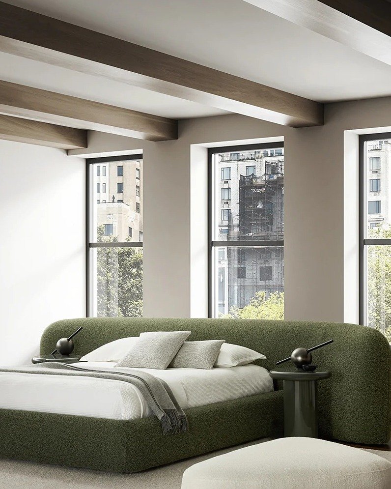 A modern bedroom featuring a large, curved bed frame and headboard completely upholstered in textured olive green fabric.