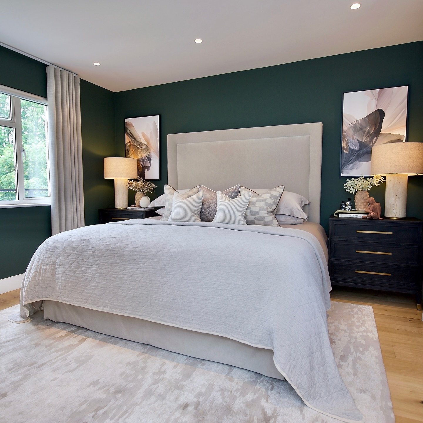 Master bedroom featuring a deep emerald green accent wall behind a tall, light beige upholstered headboard.