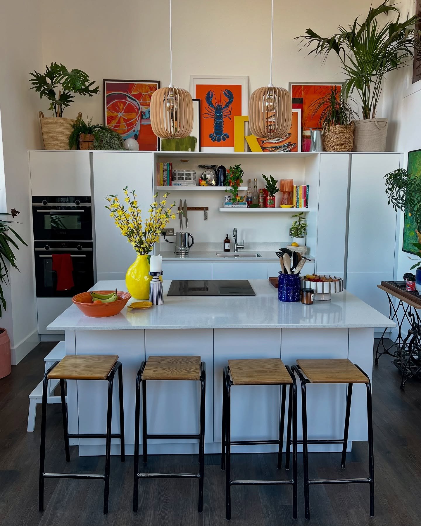 A large, colorful, contemporary painting displayed prominently on the wall of a spacious, light-filled kitchen.