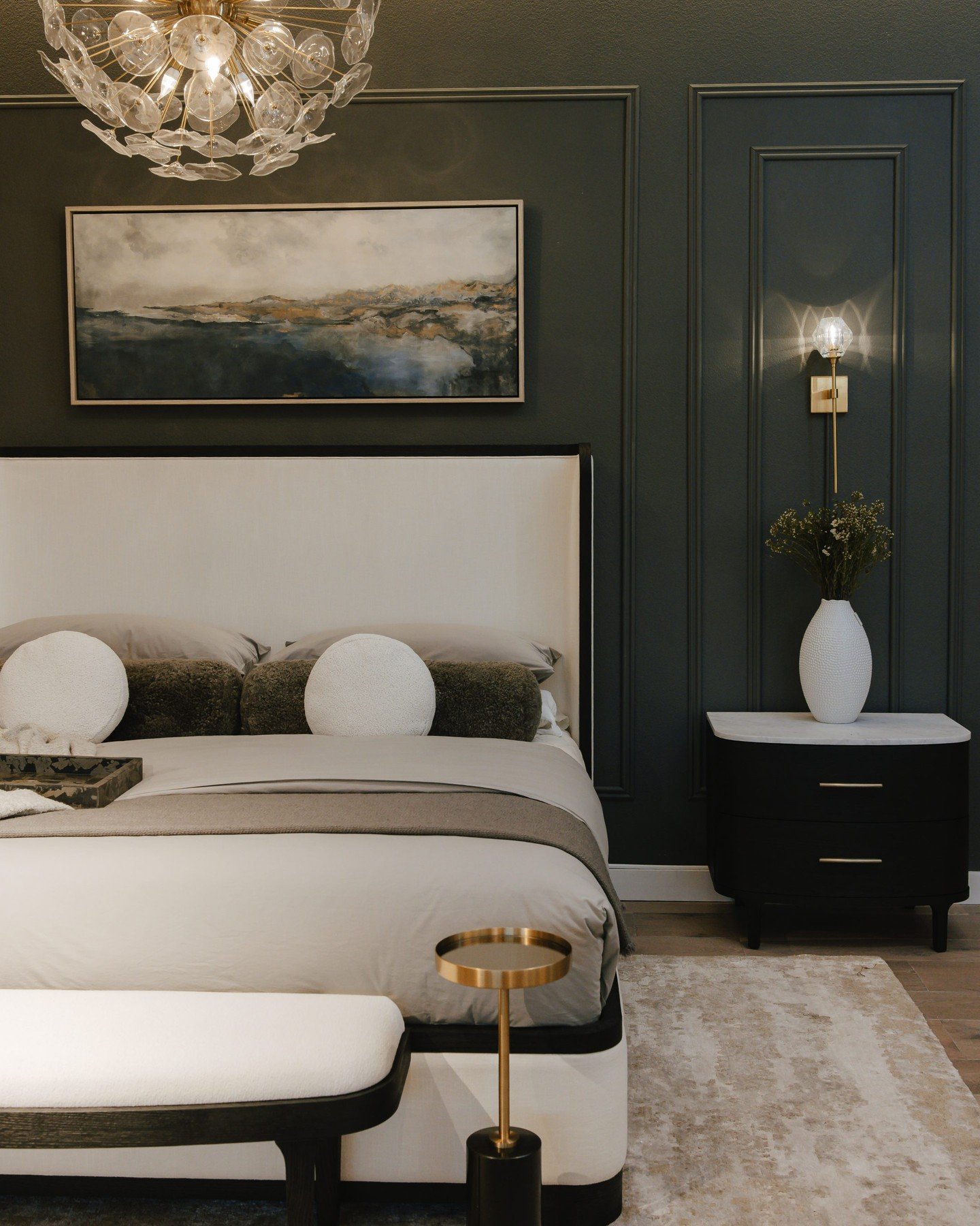 Black two-drawer nightstand with a white marble top positioned against a dark green paneled wall.