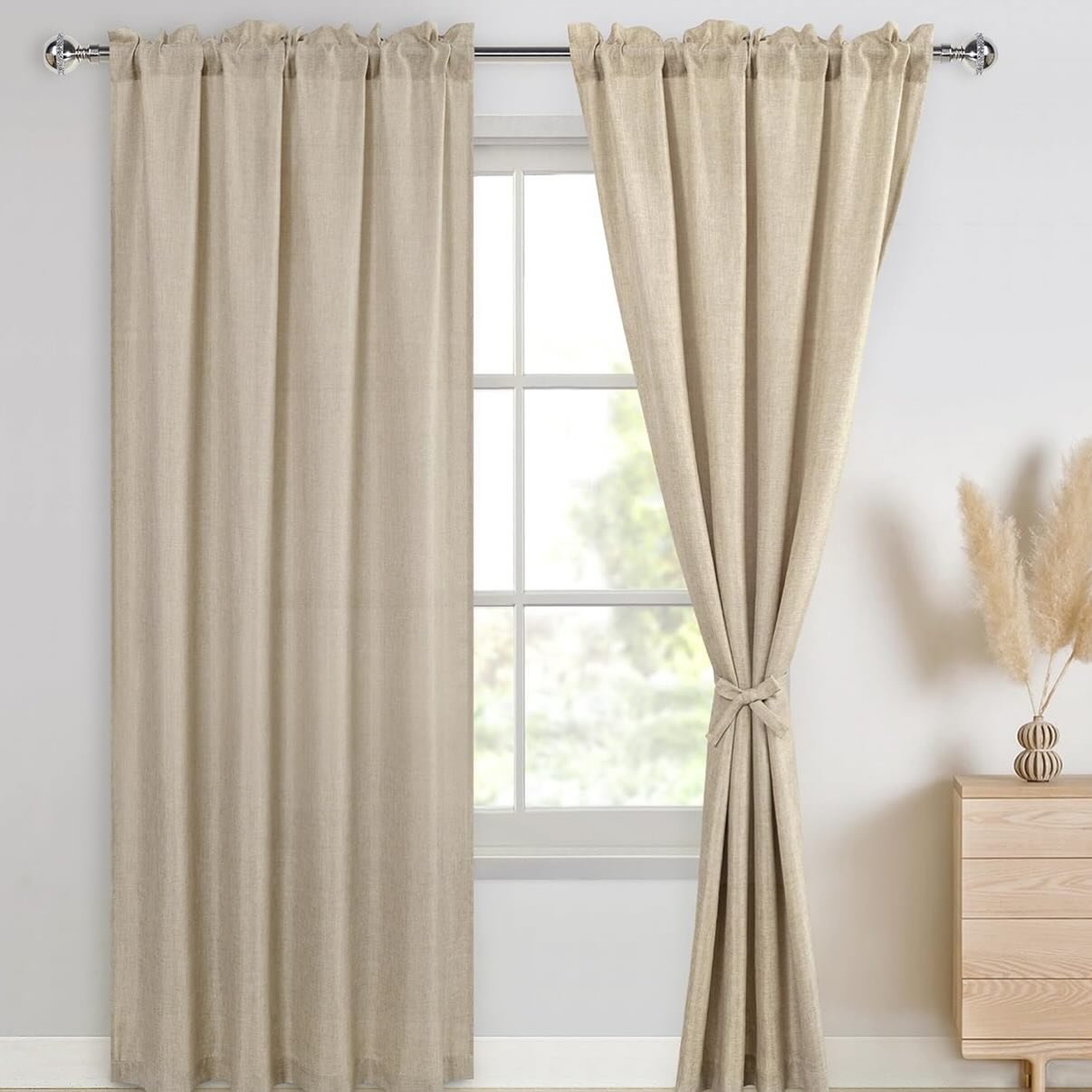 Tan, linen-textured curtains on a chrome rod; the right panel is knotted and tied back.