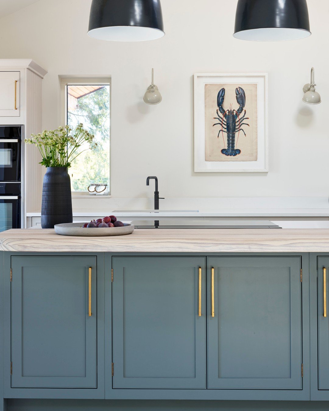 A small framed botanical print leaning on an open wooden shelf in a traditional kitchen setting.
