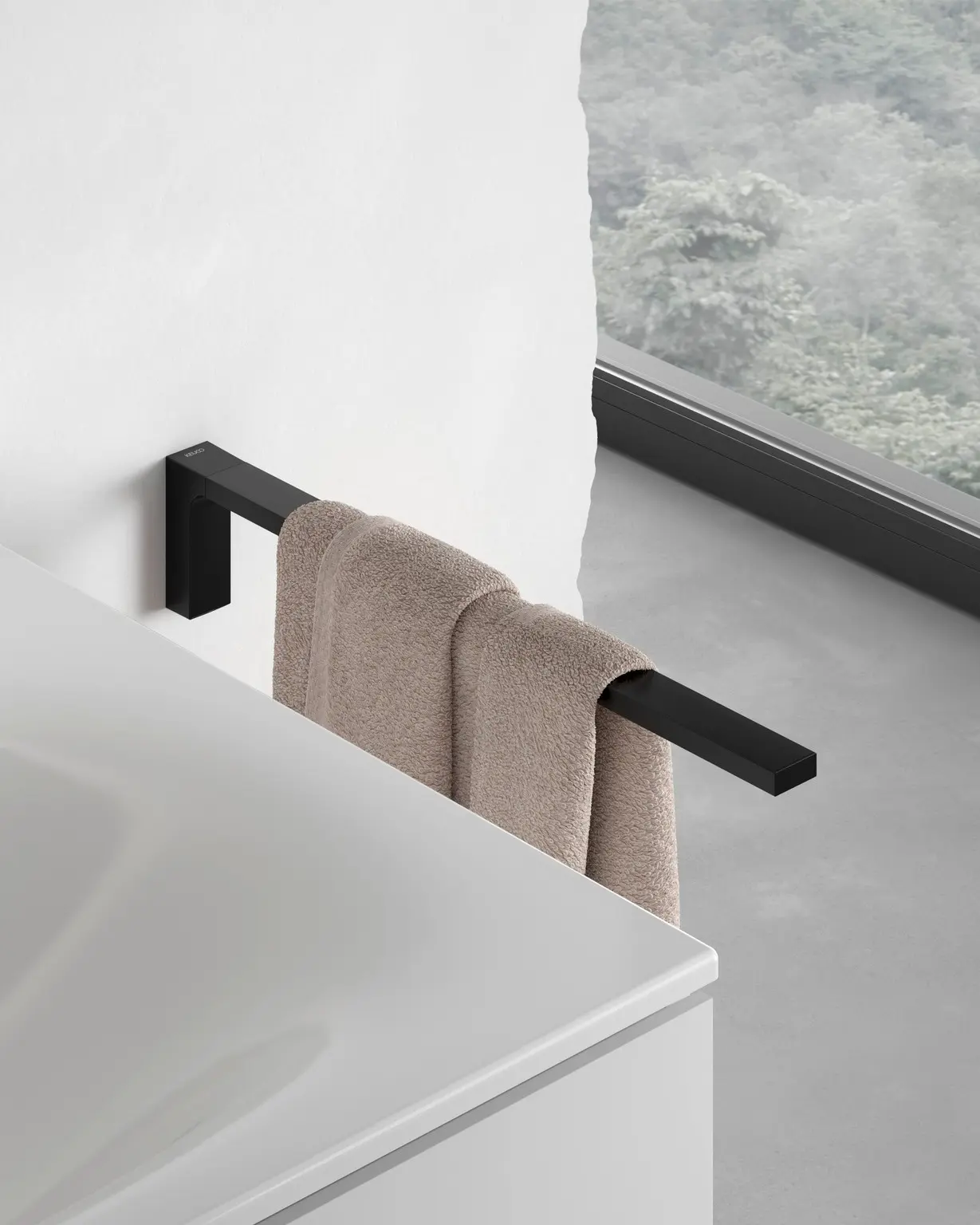 Minimalist matte black towel bar extending from a wall above a white vanity, holding a beige hand towel.