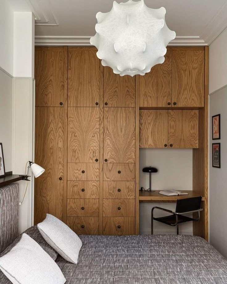 A full wall of medium-toned wood cabinetry with multiple drawers and hinged doors, featuring a recessed niche for a compact workstation.