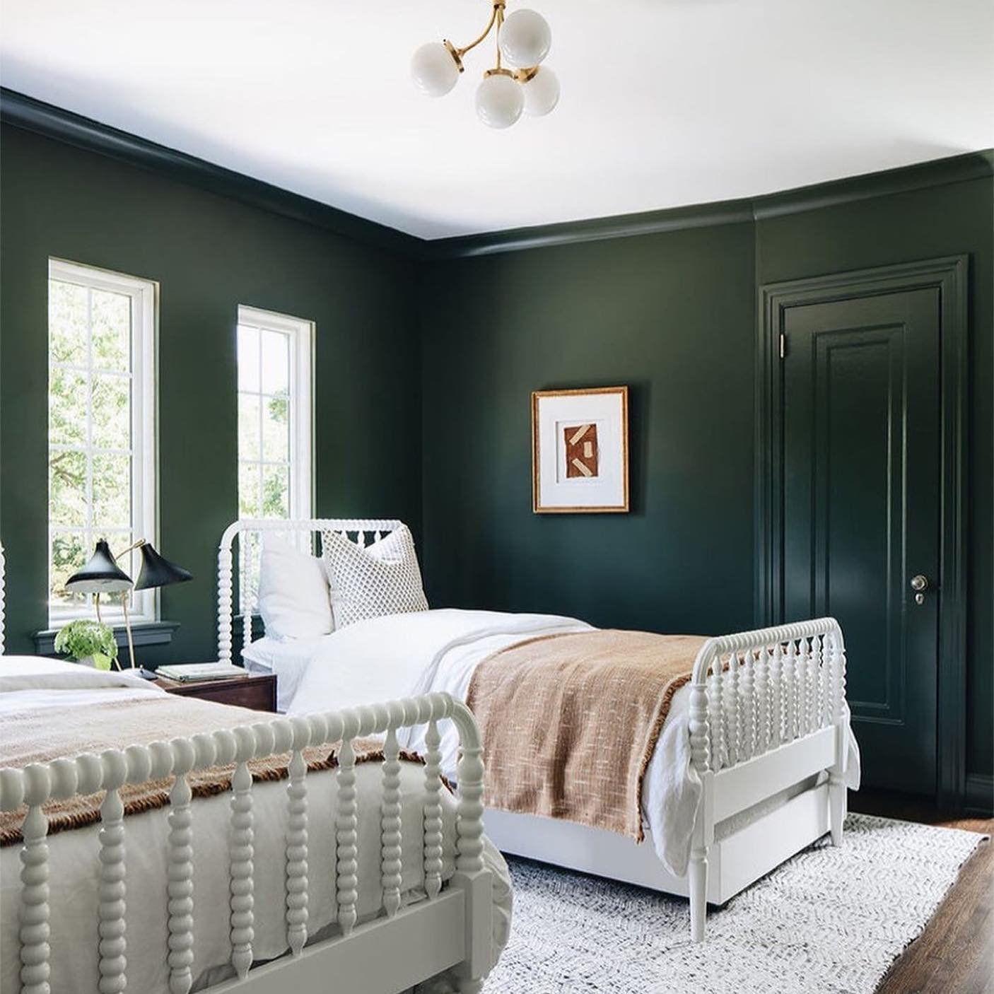 A bedroom with a dark green vertical shiplap accent wall, a simple wood bed frame, and black table lamps.