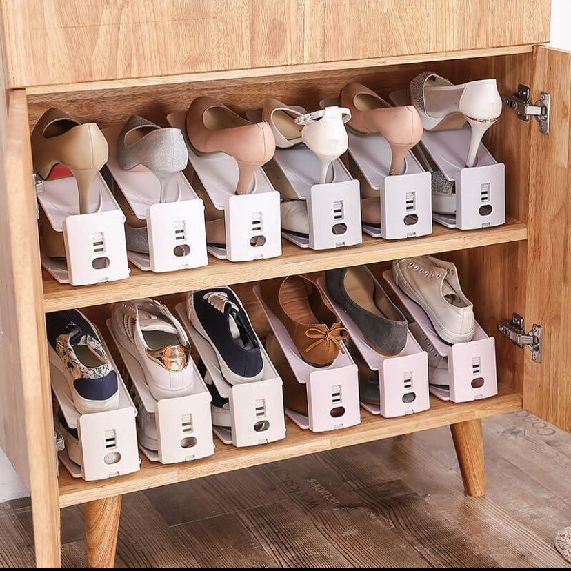 Wooden cabinet shelves filled with individual white plastic shoe slots, storing shoes one on top of the other.