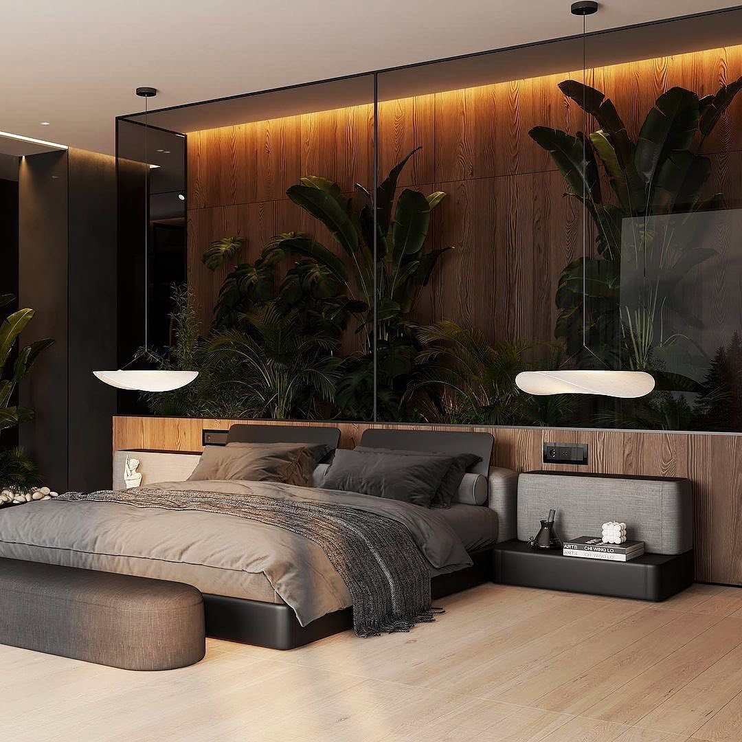 Ultra-modern dark bedroom featuring a wood-paneled wall with recessed lighting, large tropical plants behind a glass partition, and minimalist grey bedding.
