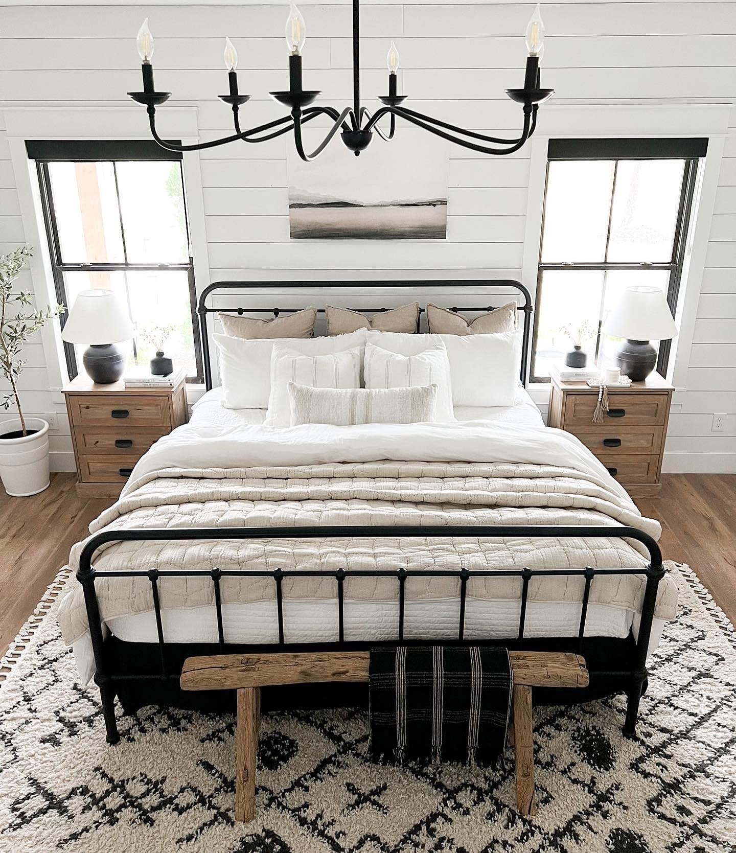 Modern farmhouse bedroom with horizontal shiplap walls, a black metal bed frame, and natural wood nightstands.
