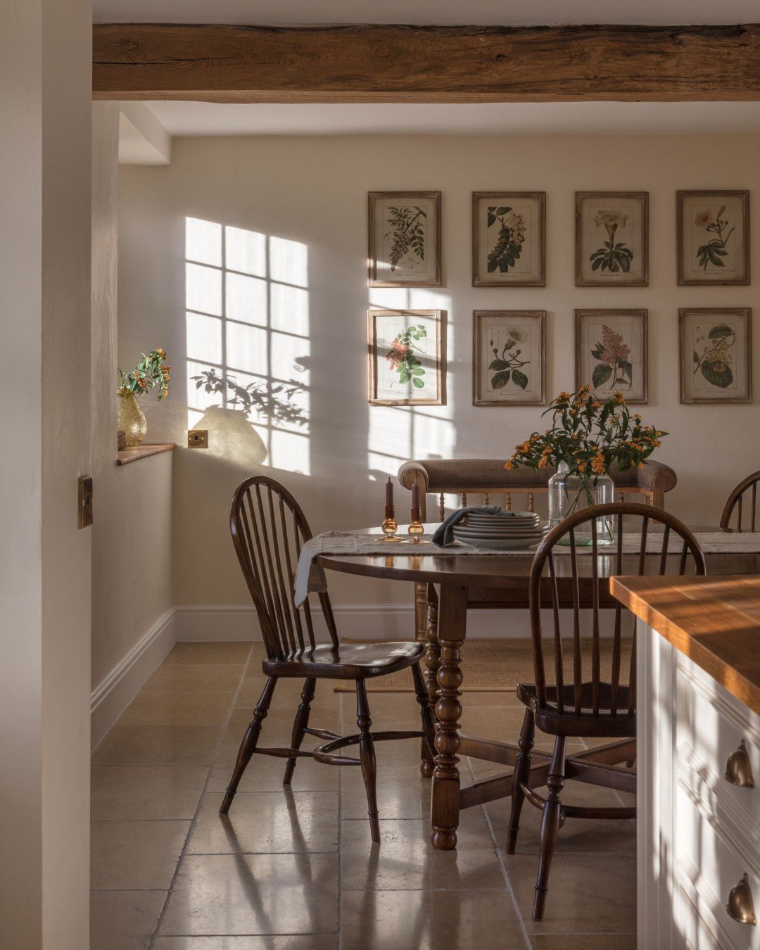A framed black and white drawing hanging in the space above a traditional range cooker in a kitchen with classic cabinetry.