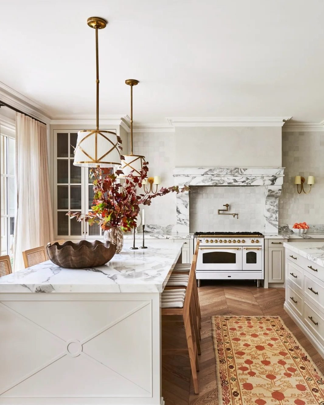 Long, horizontal linear suspension light with multiple small glass shades over a kitchen island.
