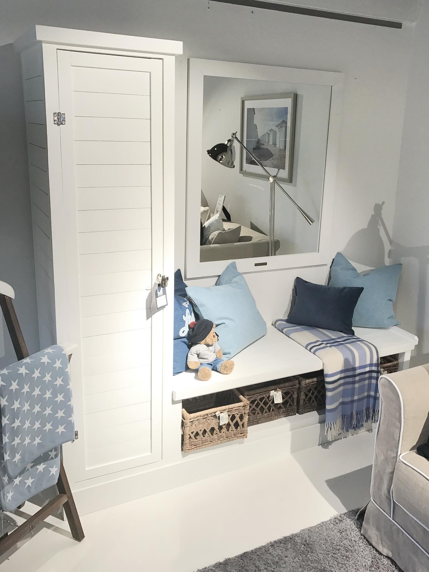 White shiplap-style built-in unit featuring a tall, narrow cupboard and a deep bench seat with lift-up access and woven baskets underneath.