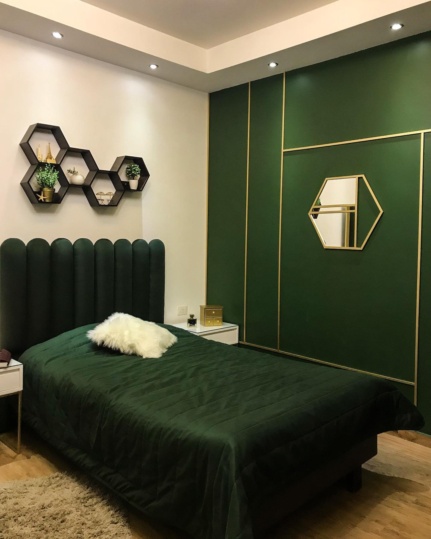 A modern bedroom with a solid dark green accent wall, white bedding, and a simple floating wood nightstand.