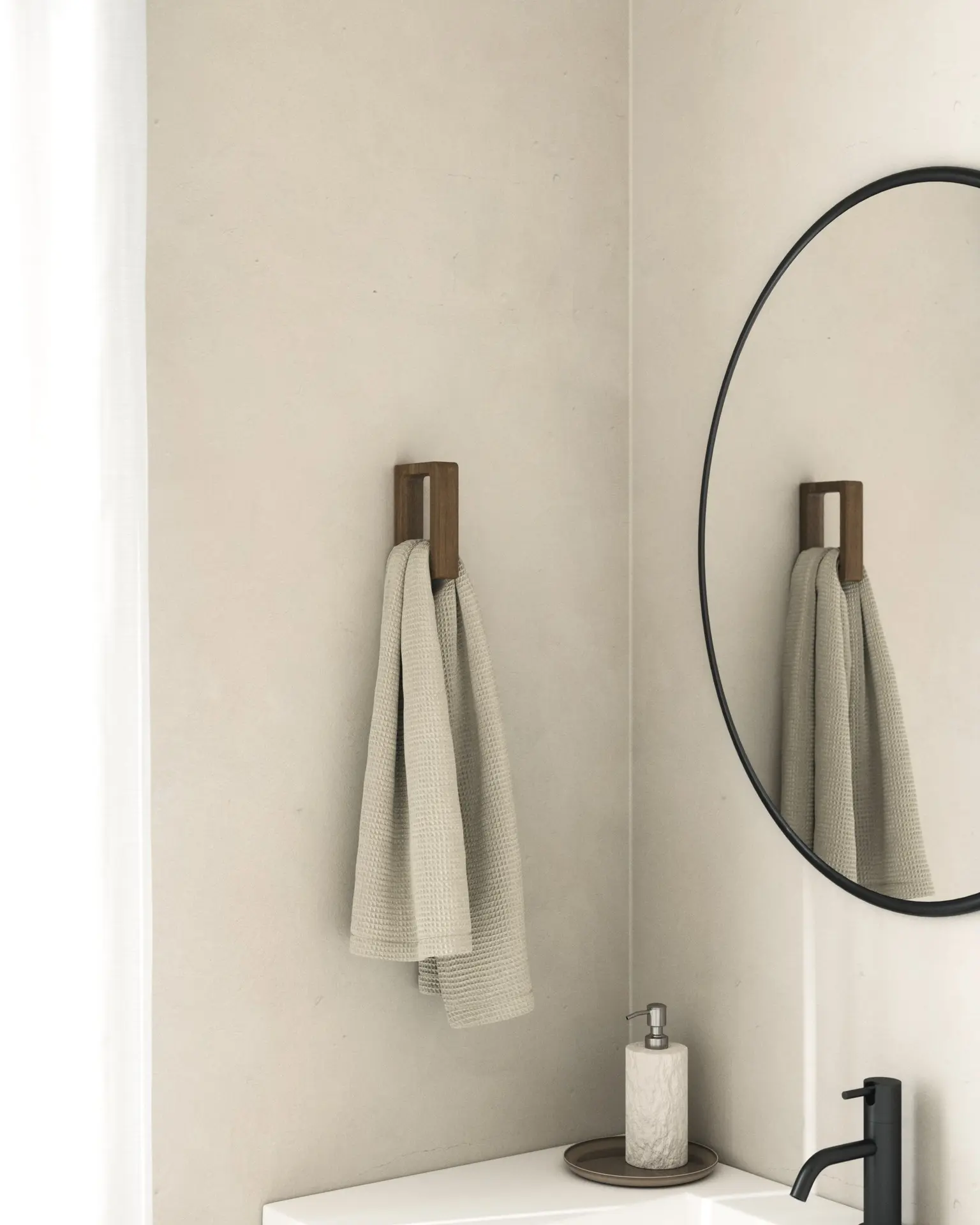 A dark walnut wood hook holding a beige waffle-weave hand towel mounted in a bathroom corner.