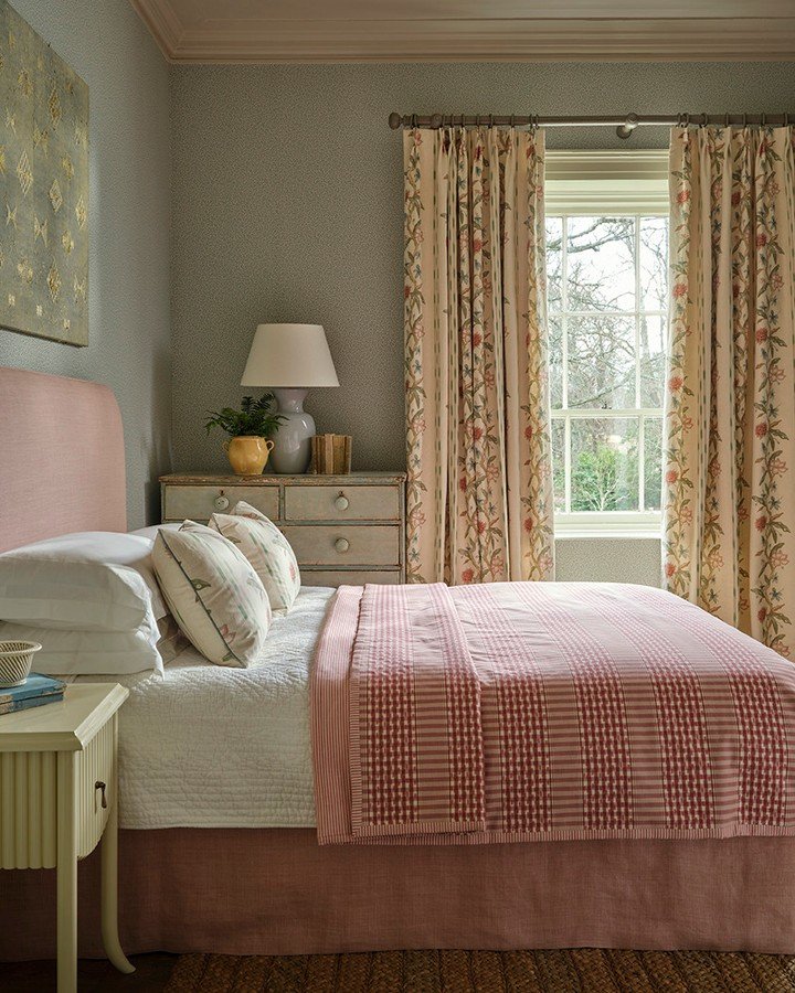 Traditional floral pinch-pleat curtains in a cozy bedroom with pink bedding and painted furniture.