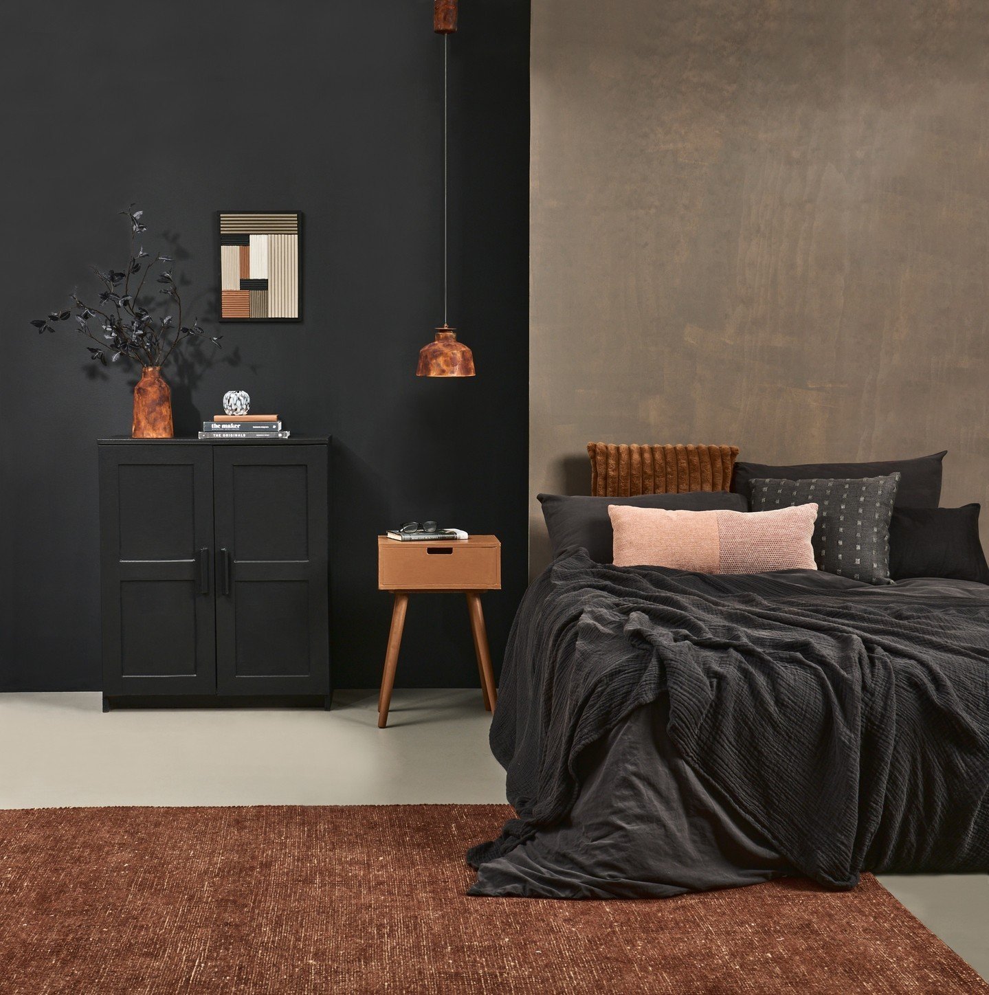 Dark bedroom with a two-toned wall—half matte black and half textured taupe—featuring a black linen bed, terracotta rug, and mid-century modern furniture.