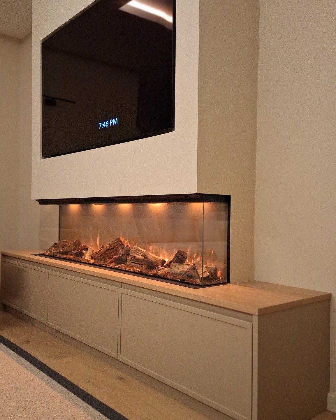 Ultra-modern living room with a long, three-sided see-through electric fireplace cantilevered above a low-profile media console, with a TV mounted above.