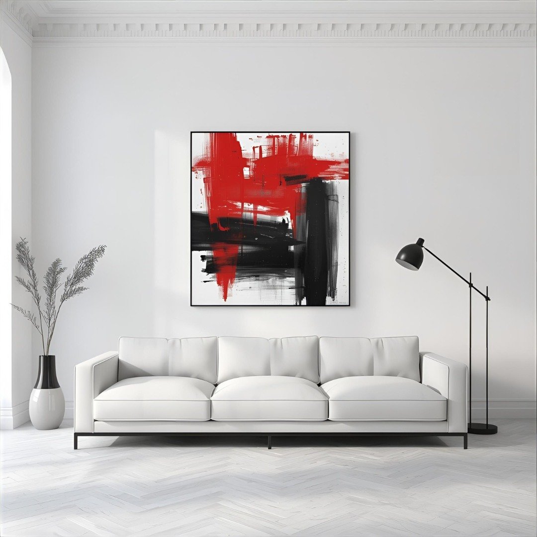 Square abstract painting with thick, expressive red and black brushstrokes, framed in black and hung above a white modern sofa.