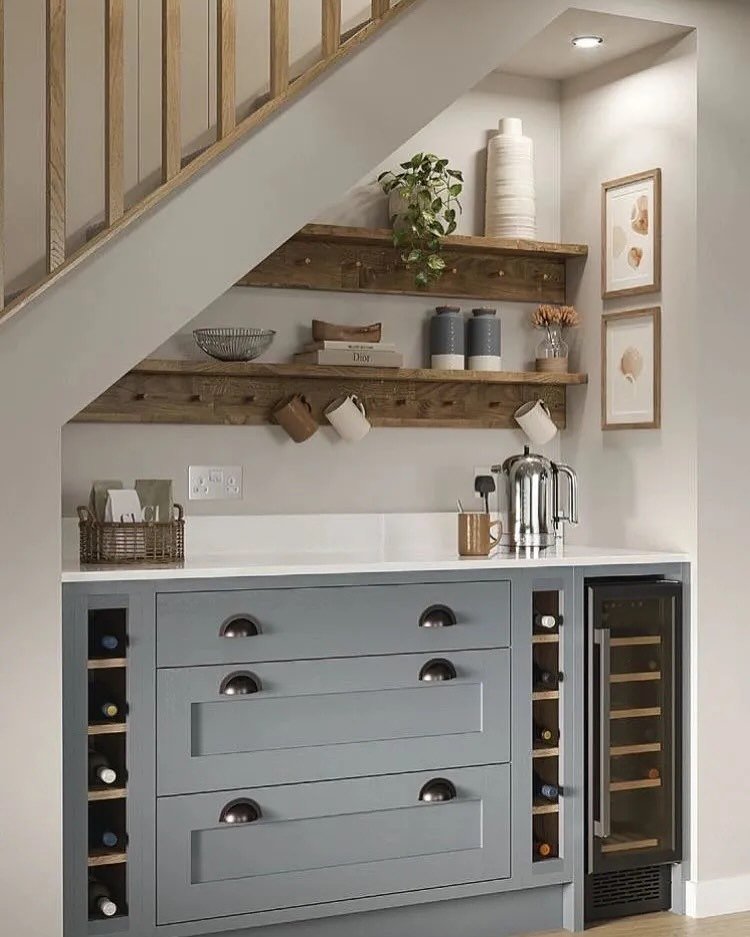 Custom blue-gray cabinet with drawers, a counter for a coffee bar under stairs.