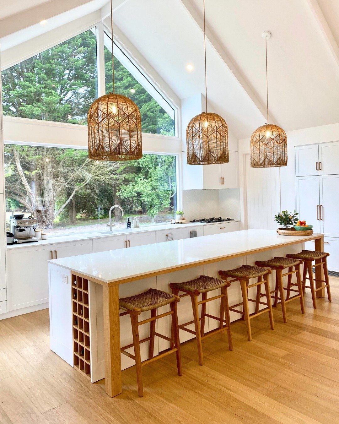 Three simple, clear glass cylinder pendants with exposed hardware over a kitchen island.