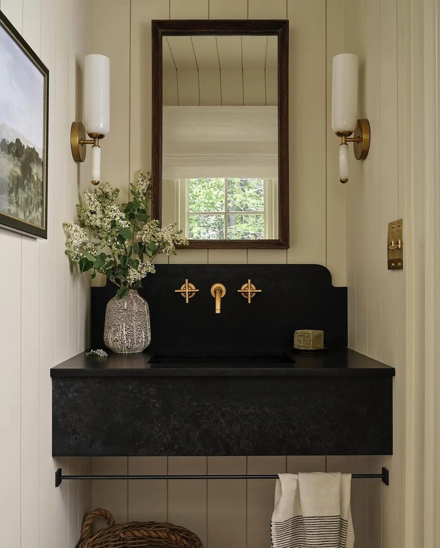 Black stone console sink with black basin and a bronze towel bar, set against light beige vertical shiplap paneling.