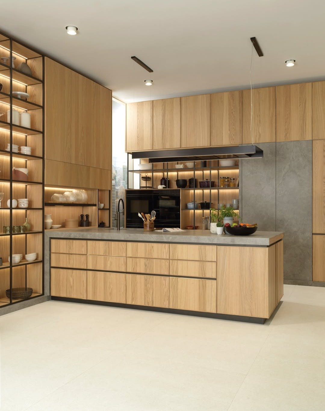 A contemporary kitchen featuring extensive vertical oak wood cabinets, a central island with a concrete-look countertop, and illuminated black metal open shelving for display.