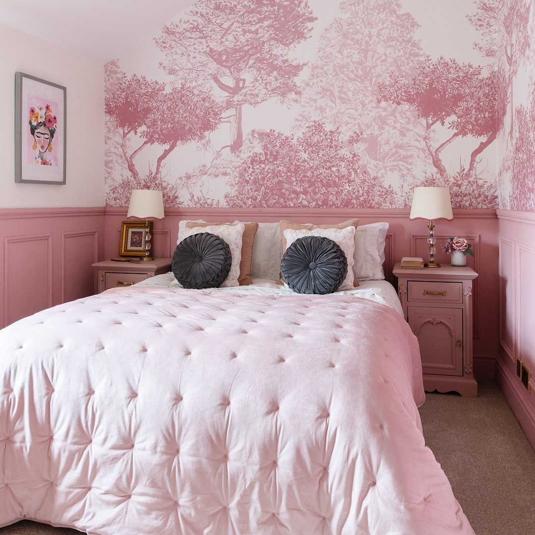 Bedroom with a large-scale pink and white tree toile wallpaper, matching dusty rose paneling, and tufted velvet bedding.