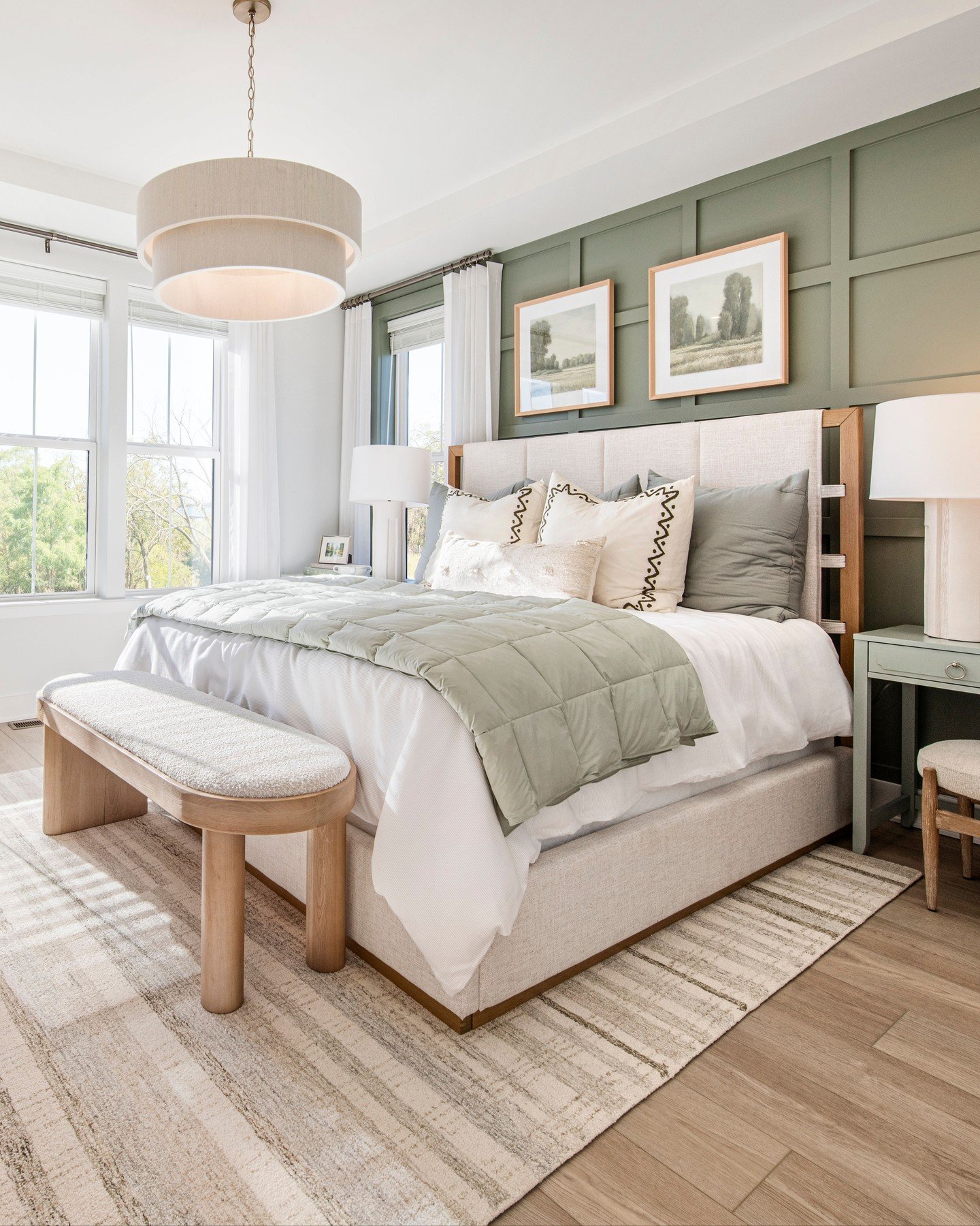 Bright, modern bedroom with a slatted green accent wall behind a beige upholstered bed and large windows. 