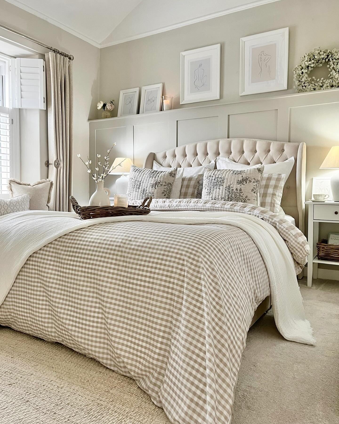 Cozy farmhouse bedroom with tufted upholstered headboard, tan gingham duvet, and a picture ledge with framed art.