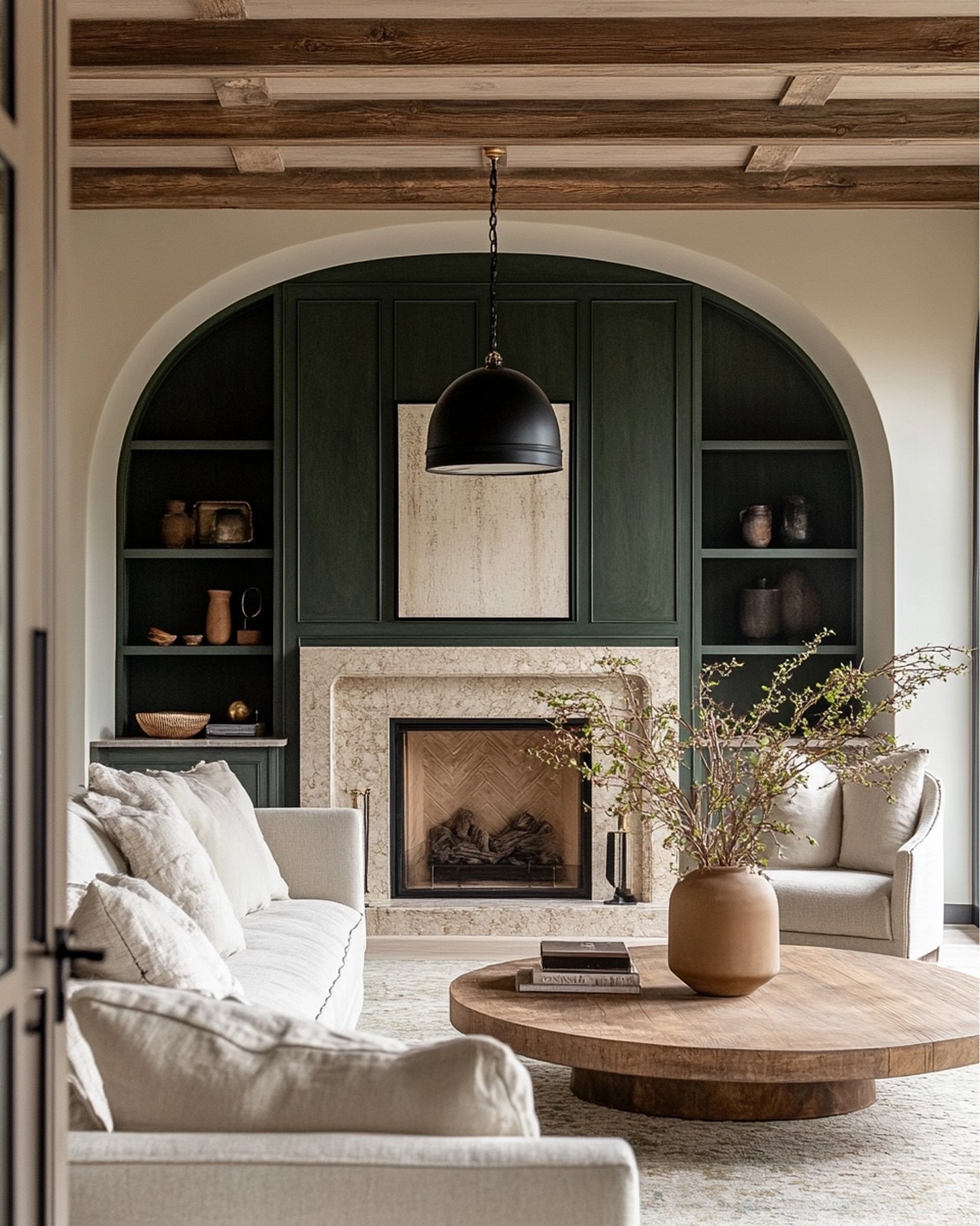 Living room with a white arched niche featuring deep green built-in shelving, a natural stone fireplace surround, and distressed ceiling beams.