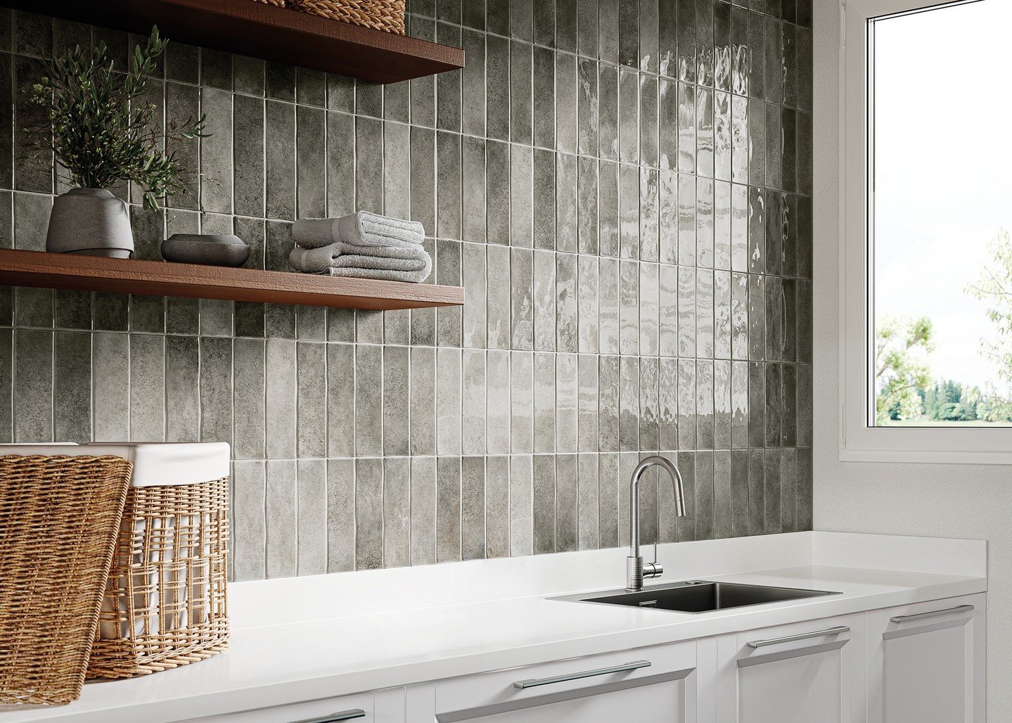 Utility room backsplash with glossy, dark gray-green elongated subway tiles arranged vertically, contrasting with white countertops and dark wood floating shelves.