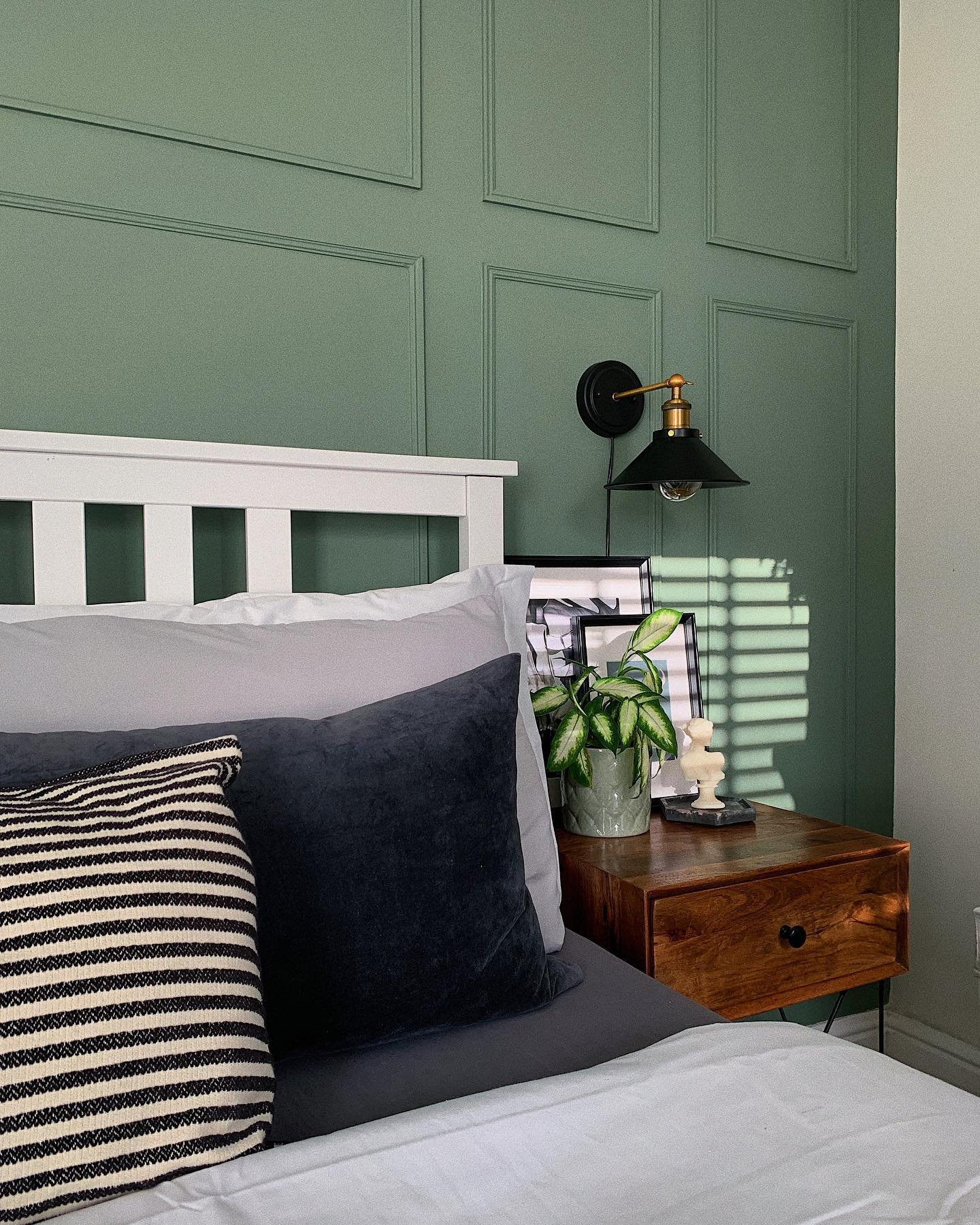 Bedroom with a textured sage green accent wall featuring square architectural paneling and a white headboard.