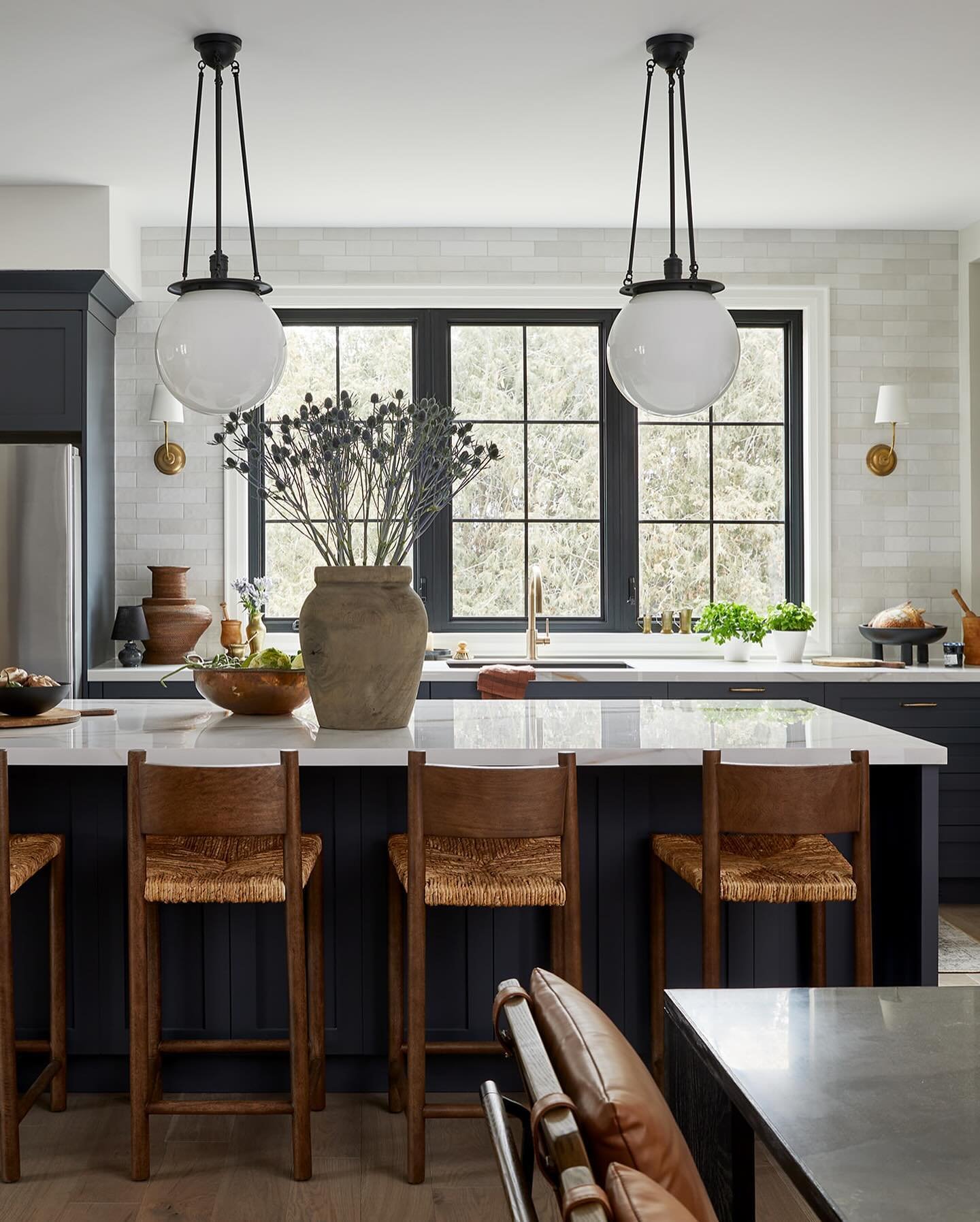 Antique brass pendants with ribbed clear glass shades hanging over a dark wood kitchen island.