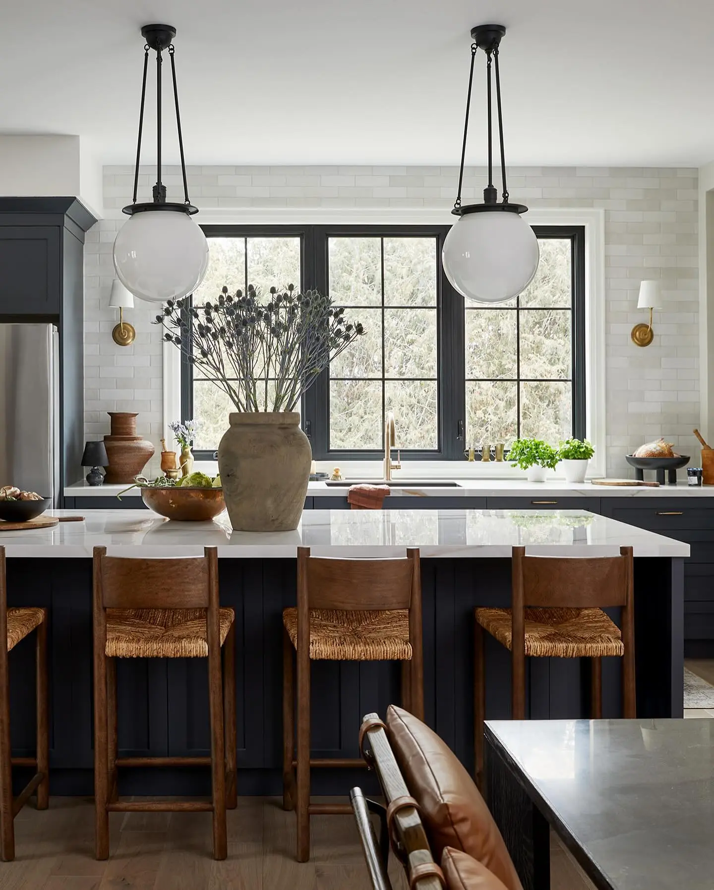 Antique brass pendants with ribbed clear glass shades hanging over a dark wood kitchen island.