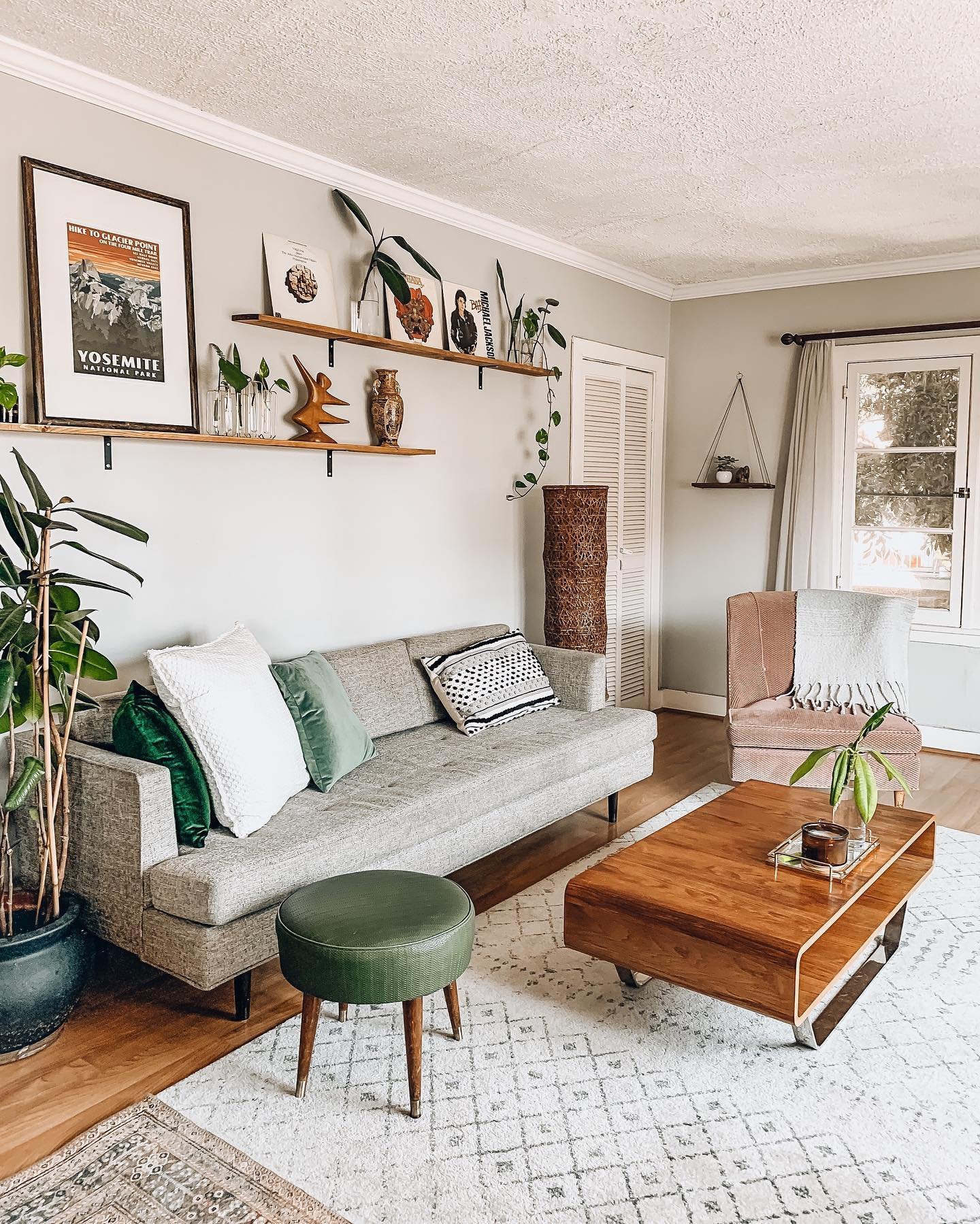 Two staggered wooden shelves holding vinyls and framed art on a living room wall