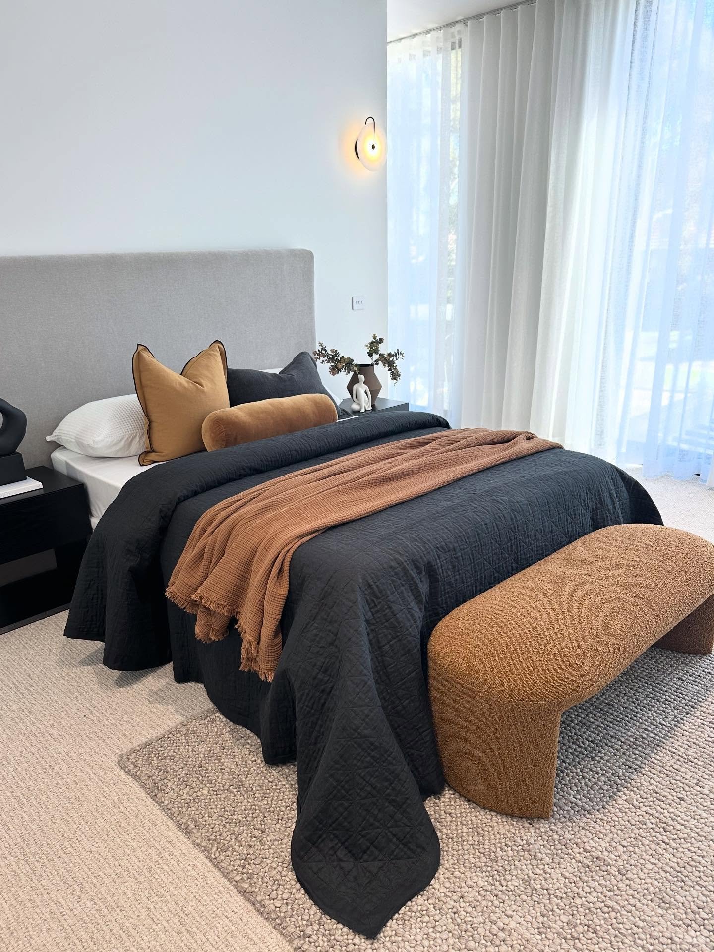 Bedroom with black duvet and tan bouclé bench