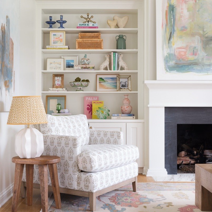 White built-in shelves next to a fireplace styled with colorful books and woven boxes
