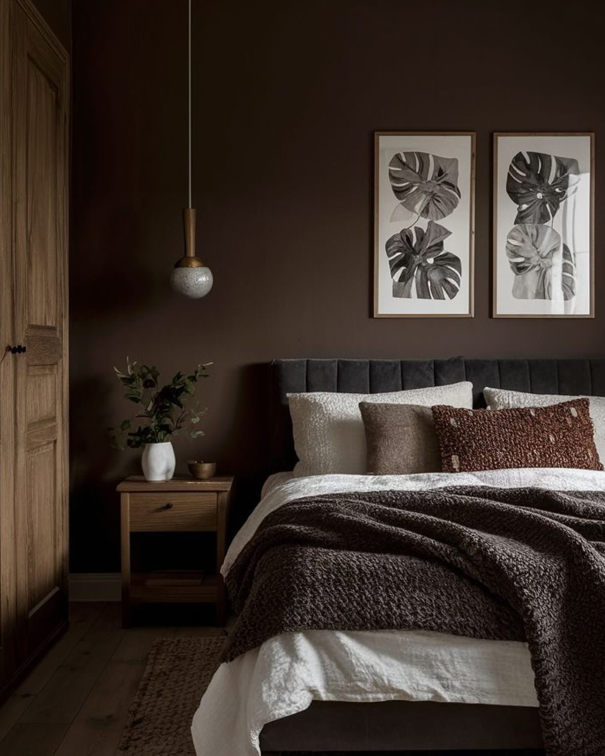 Dark brown bedroom featuring a tufted headboard and wooden accents next to botanical wall art