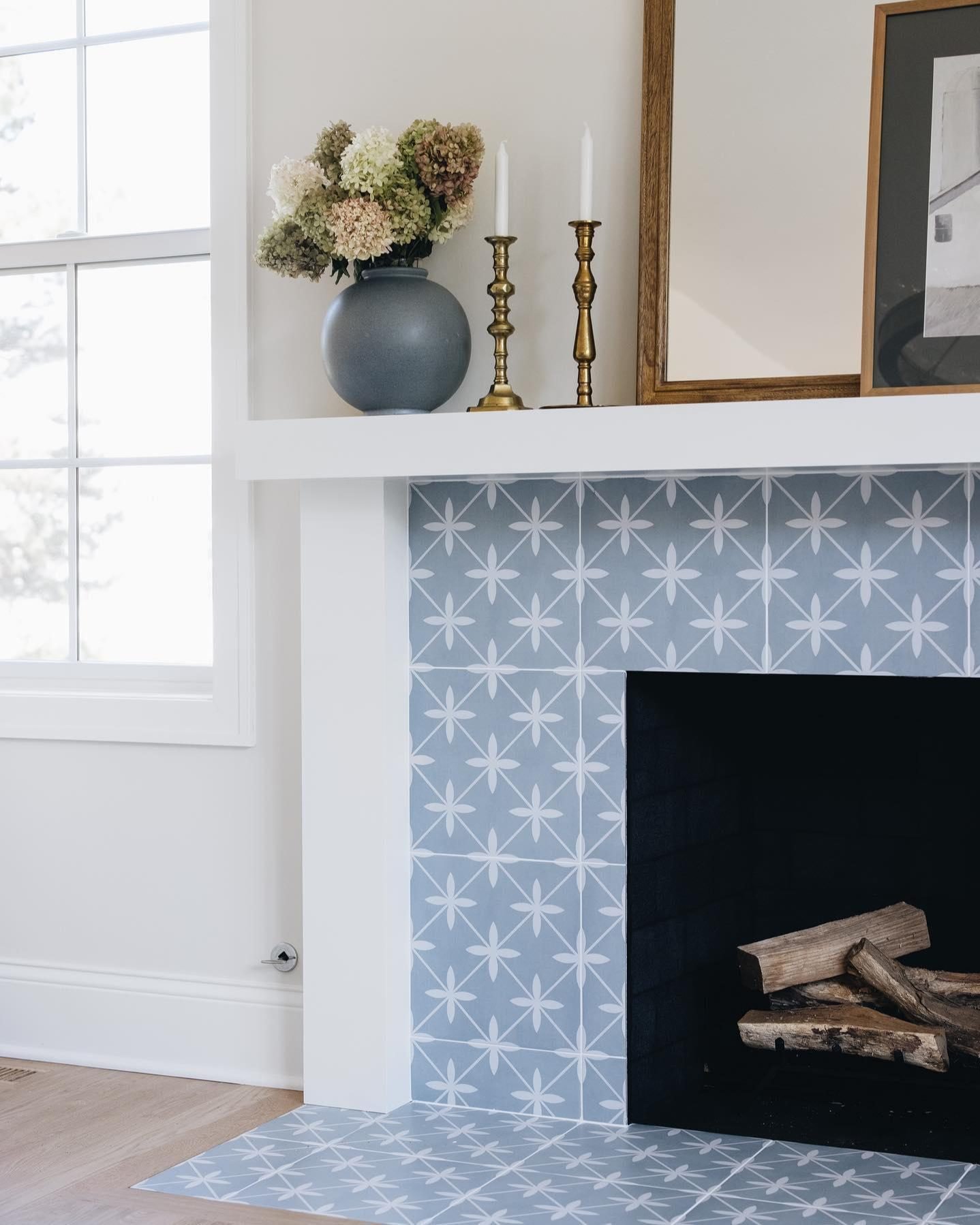 A white fireplace surround featuring light blue and white patterned cement tiles on the face and hearth.