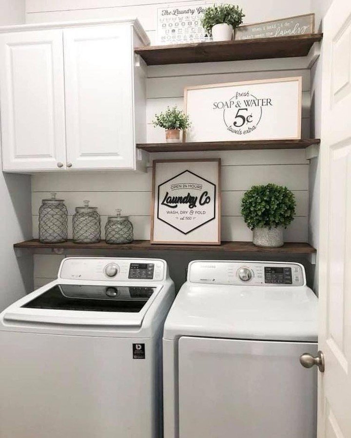 Dark stained wood shelves mixed with white cabinets above a washer and dryer featuring laundry signs