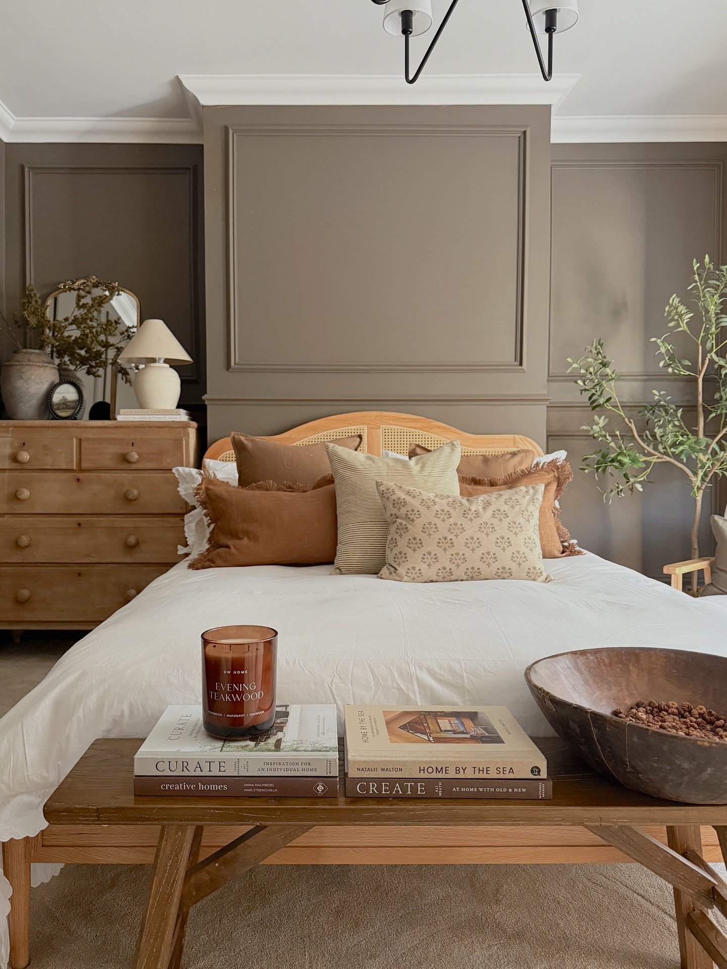 Mushroom brown bedroom with paneled walls, rattan headboard, and wooden bench at the foot of the bed