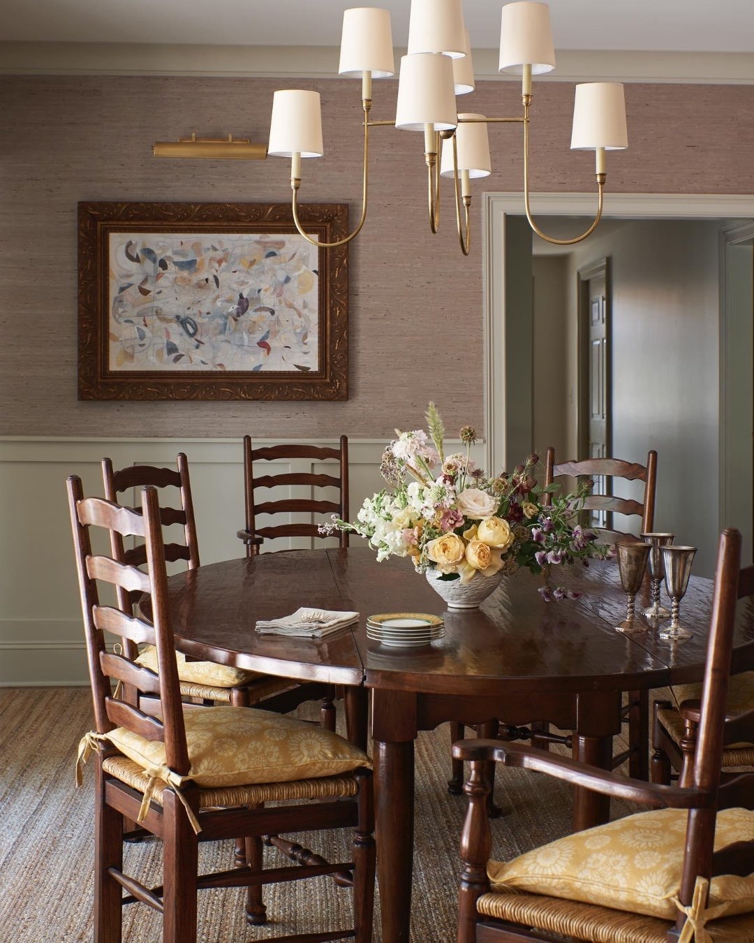 Dark wood round dining table with ladder back chairs and yellow cushions