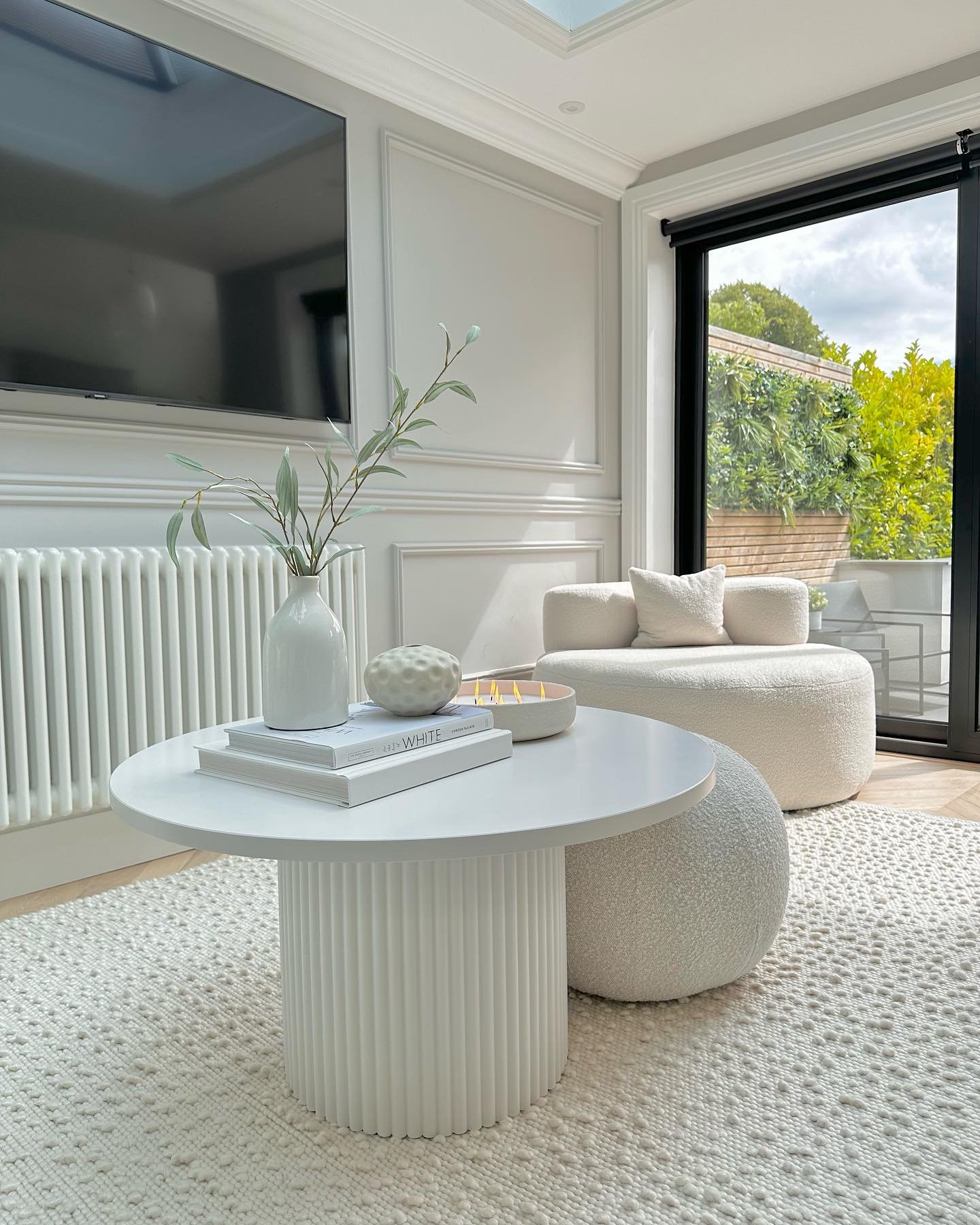 Round white coffee table with ribbed base in a bright modern living room