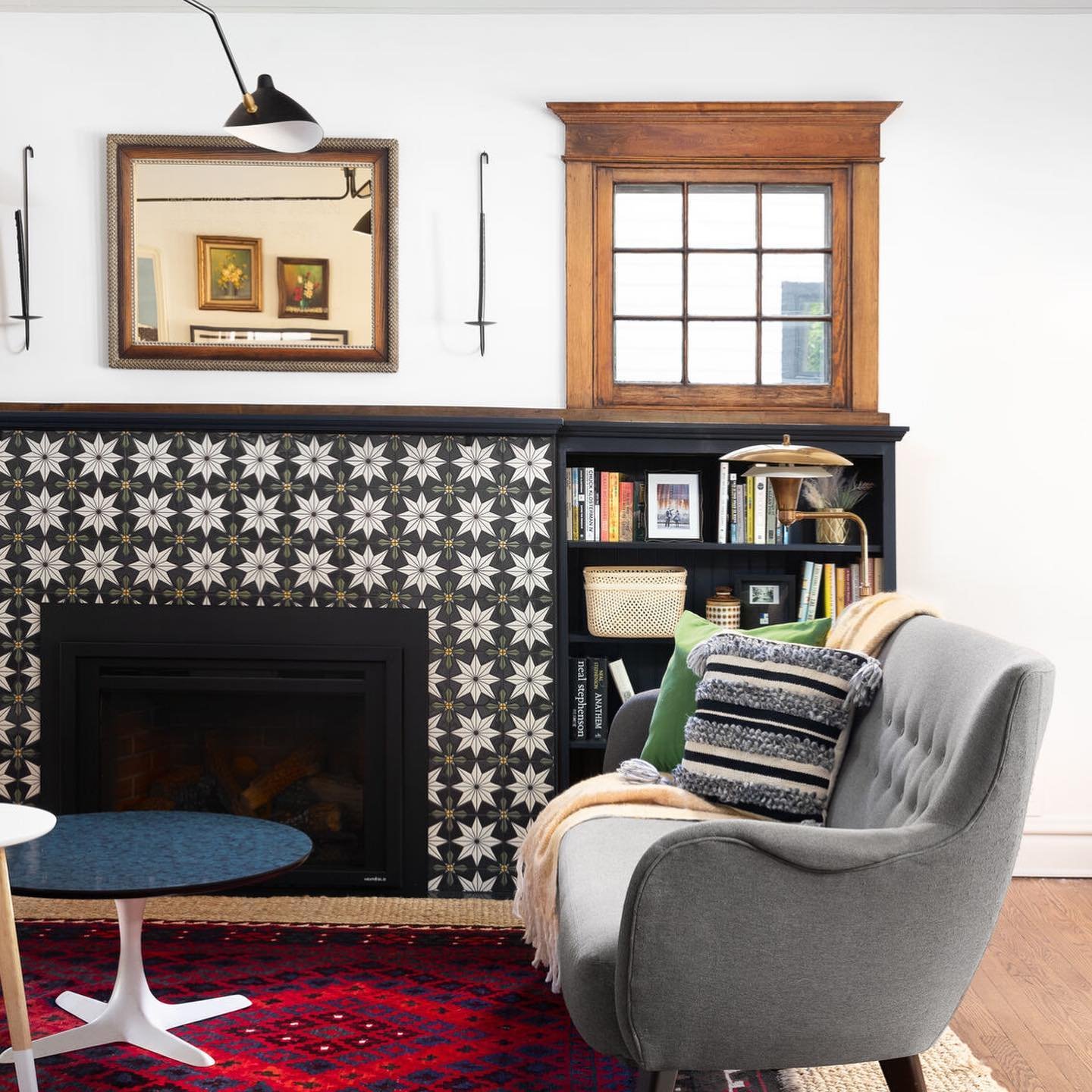 A cozy living space featuring a fireplace framed by black, white, and gold starburst patterned decorative tiles.