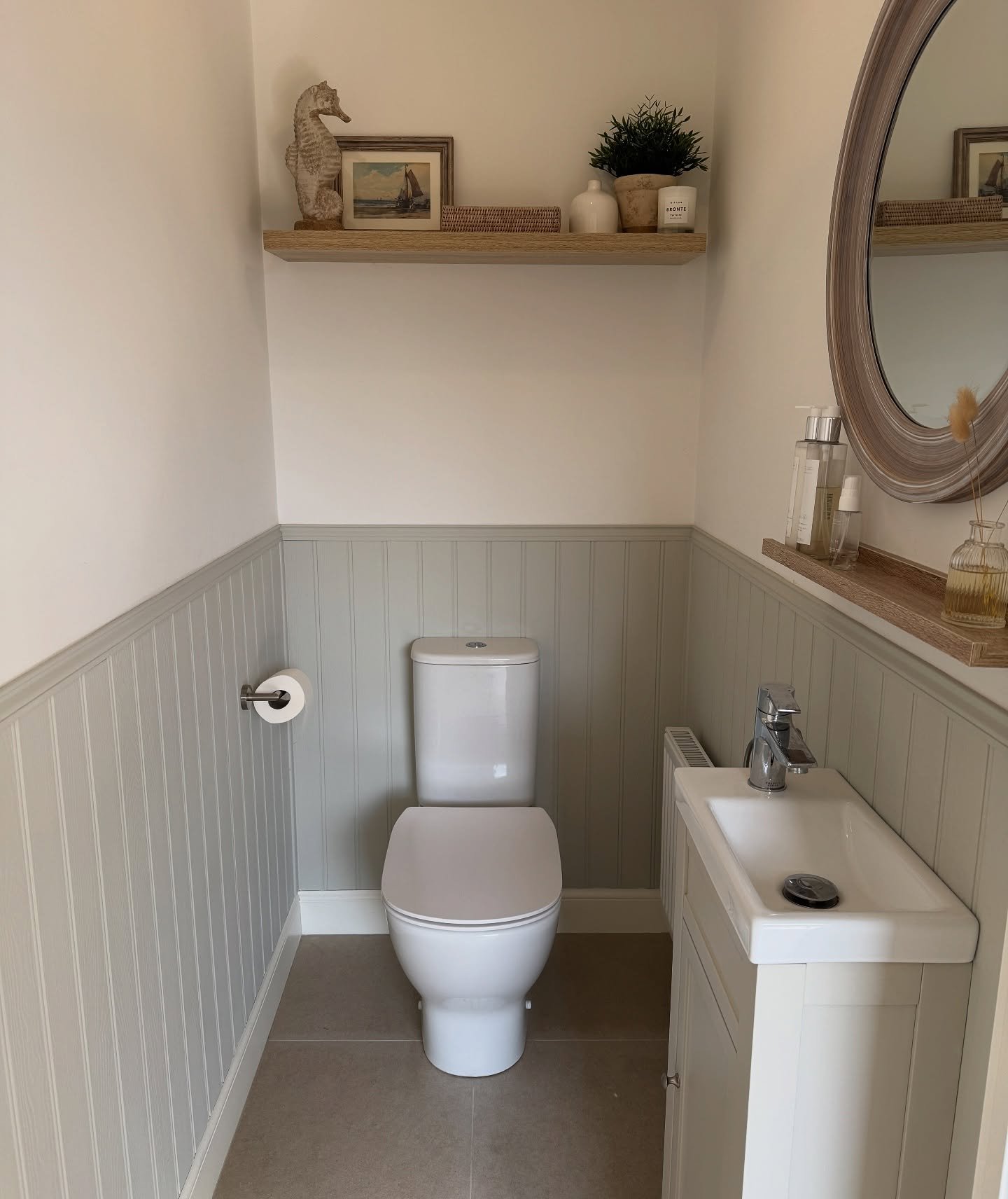 Single light wood floating shelf mounted high in a small powder room